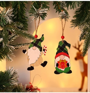 Close-up of two festive wooden gnome ornaments with candy cane and gift box on a tree
