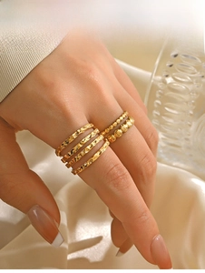 Detail of stacked gold hammer textured rings and beaded bands on a model hand