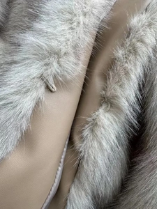 Detail of light gray faux fur collar with tan leather lining and elastic buckle fastener