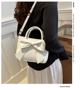 Detailed back view of a white bow shoulder bag on a model for size and style reference