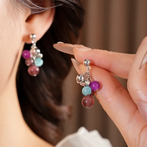 Detail of colorful cat eye stone tassel earrings with silver beads and needle design