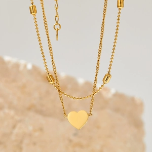 Elegant gold double-layered heart anklet with beads on a soft rocky background