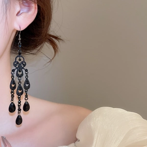 Detail of vintage black waterdrop chandelier earrings worn by a model in a close-up shot