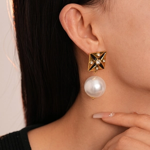 Detail view of vintage pearl drop earring with black enamel star and crystal inlay