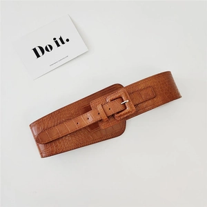 Close-up of brown crocodile texture belt with a large square leather buckle on a clean background