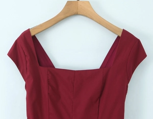 Détail de la robe bordeaux avec laçage au dos et encolure carrée sur un cintre en bois