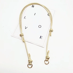 Close-up of golden braided shoulder strap featuring metallic rings and knotted details