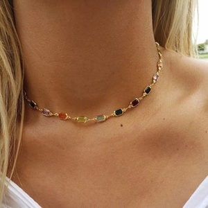 Close-up of golden choker chain necklace with colorful rectangle natural stones on model
