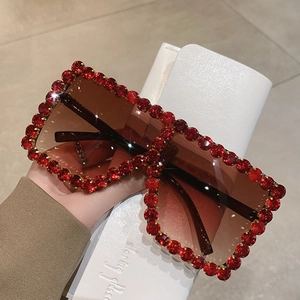 Macro shot of oversized square sunglasses featuring premium red crystals and golden base