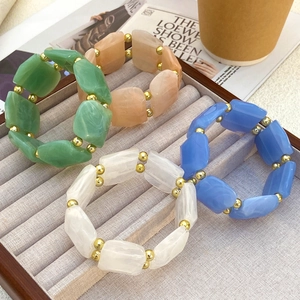 Nahaufnahme von vier bunten Harzperlen-Armbändern mit Goldakzenten auf Samtdisplay