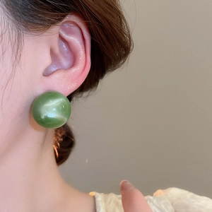 Close-up of model wearing green candy-colored round stud earring with opal-like texture
