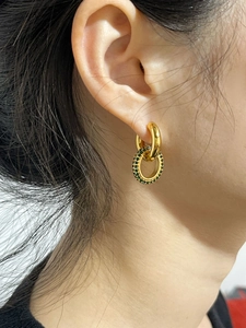 Vue détaillée des boucles d'oreilles dorées avec cristaux de zircone verts