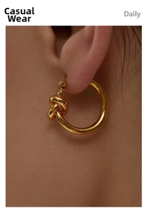 Close-up of a minimalist 18K gold knot hoop earring shown on ear for daily wear