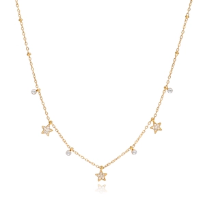 Détail du collier en acier titane doré avec breloques étoiles et glands en zircon sur blanc