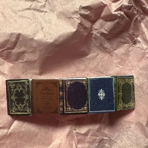 Detailed view of five vintage miniature book hair clips with gold patterns on pink paper