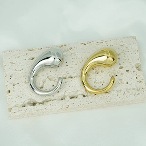 Polished 18K gold and silver chunky teardrop earrings on beige stone base
