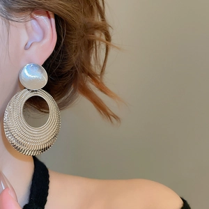 Gros plan détaillé de boucles d'oreilles créoles argentées à grain radial texturé