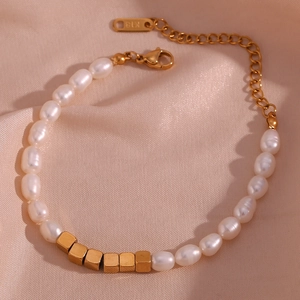 Detail of freshwater pearl bracelet with gold square beads on pink silk background