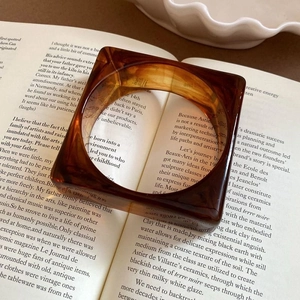 Macro shot of an amber acrylic ring placed on a book page with vintage warm tones