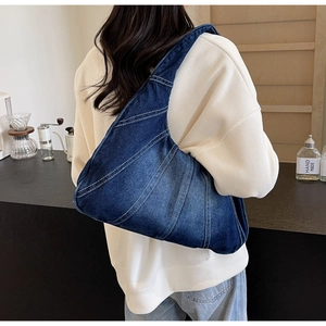 Détail du sac à épaule en jean bleu avec surpiqûres blanches sur une tenue décontractée