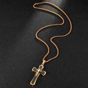 Detailed view of a layered gold and black cross necklace on a textured dark background