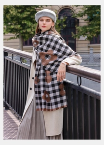 Detailed view of checkered scarf with brown floral patterns and tassels worn outdoors