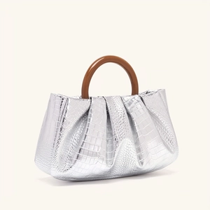 Close-up of silver crocodile pattern pleat cloud bag with a brown resin round handle