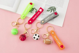 Close-up of sports ball keychains with Good Luck silicone wristbands and golden metal clips