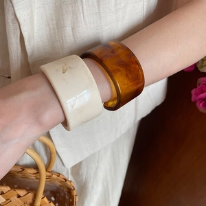 Detail of stacked cream marble and amber tortoise resin bangles on wrist