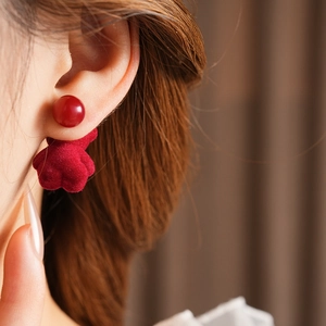 Close-up of model wearing cute red velvet bow earrings with round bead details