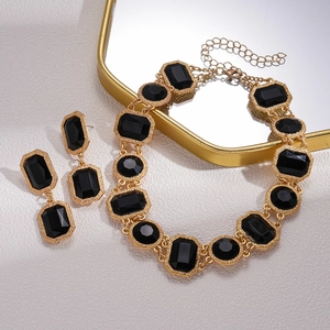 Parure bijoux rétro dorée avec cristaux noirs géométriques sur plateau miroir