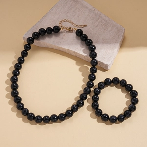 Detail of black marbled acrylic bead necklace and bracelet set with golden clasps