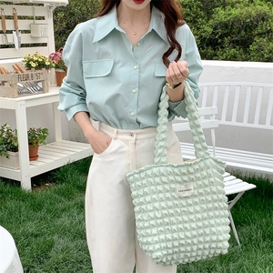 Mint green puffy bubble tote bag with floral texture held by a model in a garden