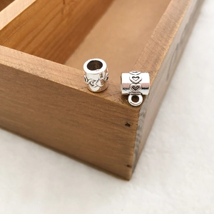 Close-up of silver heart-embossed beads and charm connector for DIY jewelry making
