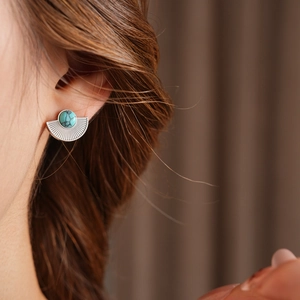 Close-up of vintage silver fan-shaped earring with turquoise stone worn by model