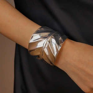 Close-up of a wide silver cuff bracelet with irregular wave texture on a model's wrist