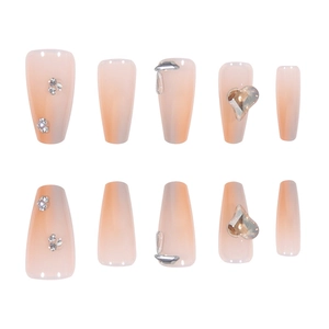 Long trapezoid press-on nails set in nude pink gradient with luxury rhinestone heart accents