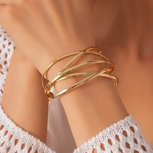 Detail of minimalist layered crossover cuff bracelet in polished gold on a wrist