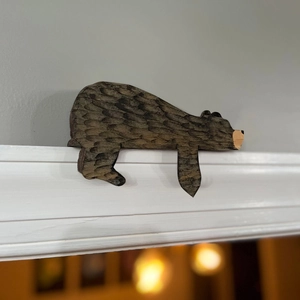 Close-up of a hand-carved wooden brown bear ornament perched on a white door frame