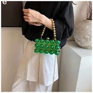 Detail of green acrylic egg bag featuring spherical beads and a golden chain strap