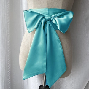 Détail d'une ceinture nœud en satin turquoise avec texture soyeuse sur un mannequin