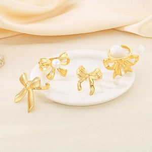 Minimalist golden stainless steel bow rings with pearl detail on elegant white tray
