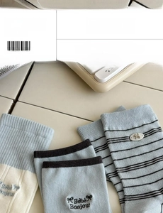 Detail of cotton socks with Bébé Bonjour embroidery and metal bow charms in blue and white