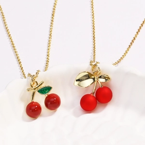 Detail of red cherry pendants with glossy and matte finishes on gold beaded chains