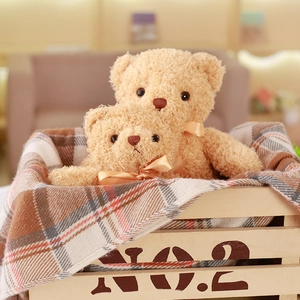 Detail of light brown teddy bears with curly fur and satin bows in a wooden basket