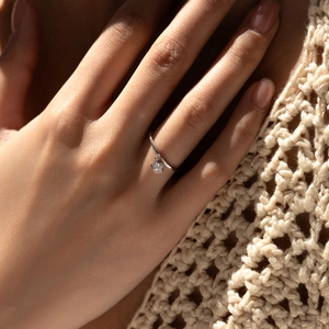 Minimalistischer S925 Sterlingsilber Sternanhänger Ring am Finger vor weichem Strickhintergrund