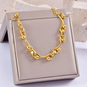 Chunky gold chain bracelet with wave bars and beads on jewelry box, punk style