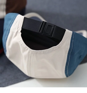 Detail view of the adjustable black buckle and strap on a blue and white baseball cap