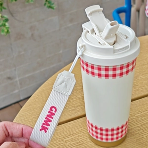 Detailed top view of a white vacuum coffee cup featuring a red gingham pattern and strap