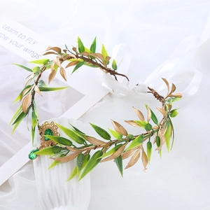 Close-up of golden leaf headband with green gemstone pendant and white ribbon tie